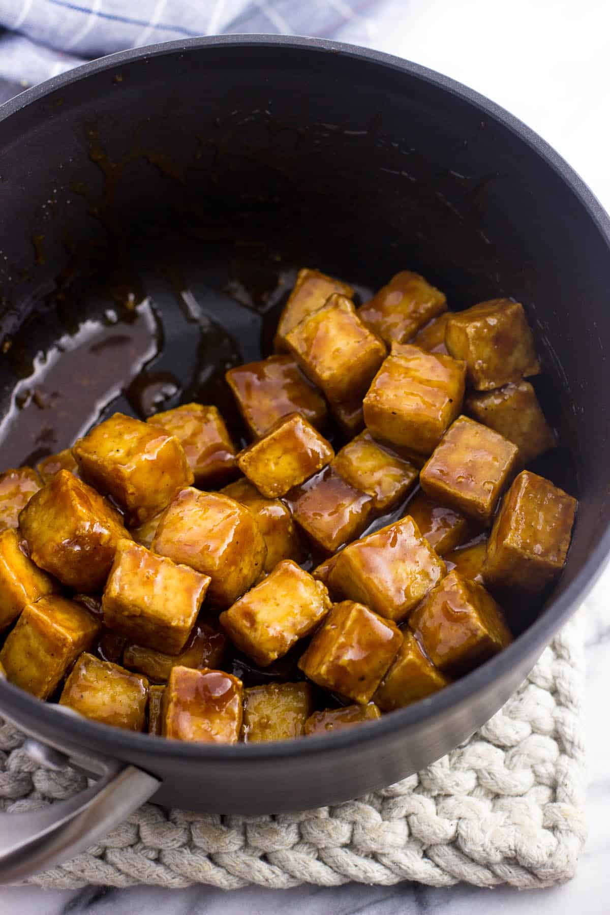 Cooked tofu cubes in a medium saucepan tossed in glaze.