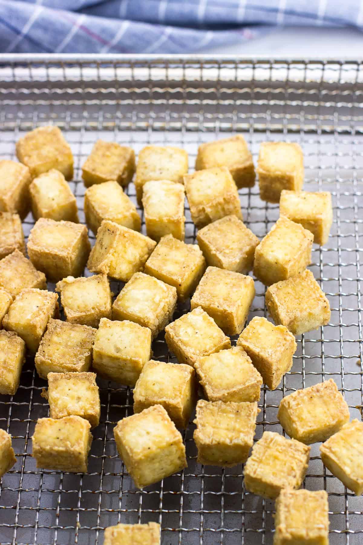 Air fried tofu cubes on a metal air fryer basket.