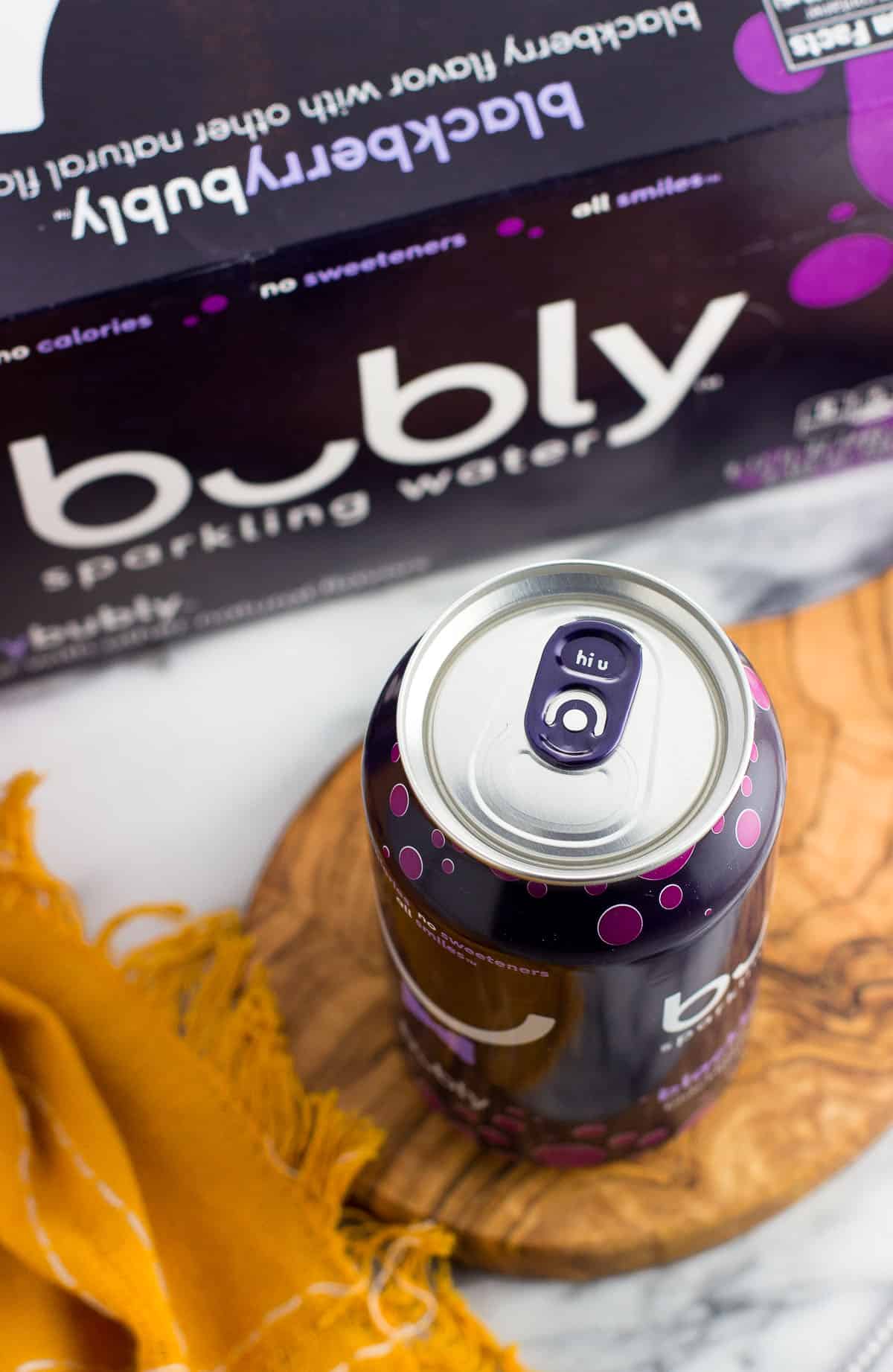 A can of blackberry bubly next to a carton of it.
