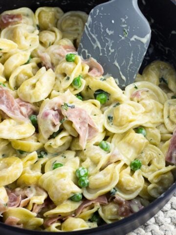 Tortellini in cream sauce with prosciutto and peas