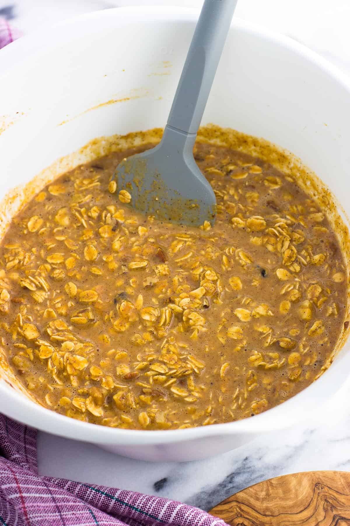 All of the oatmeal mixture stirred together in a mixing bowl with a spatula in it