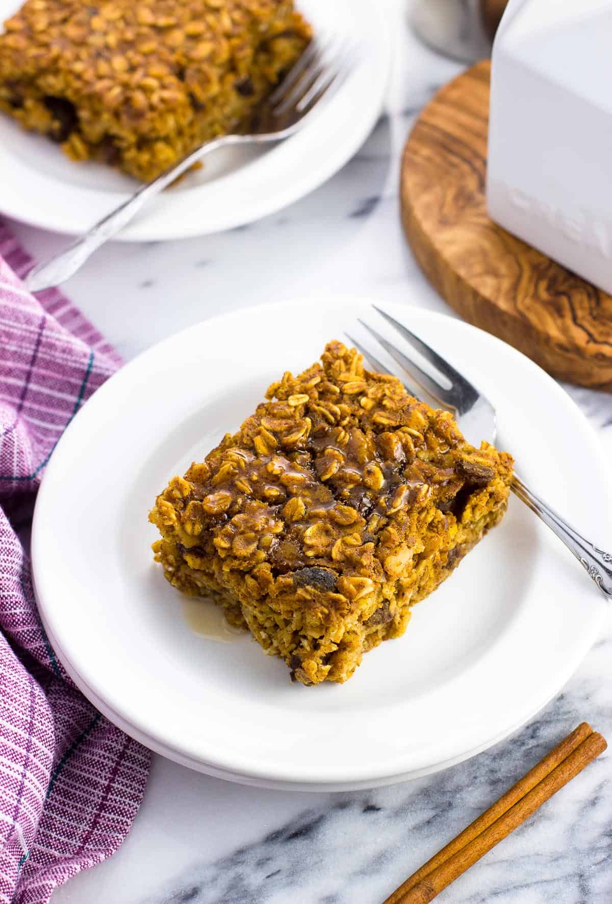 Two pieces of baked oatmeal on two small plates with forks next to them