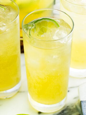 Sparkling mocktails in three tall glasses filled with ice and lime wedges
