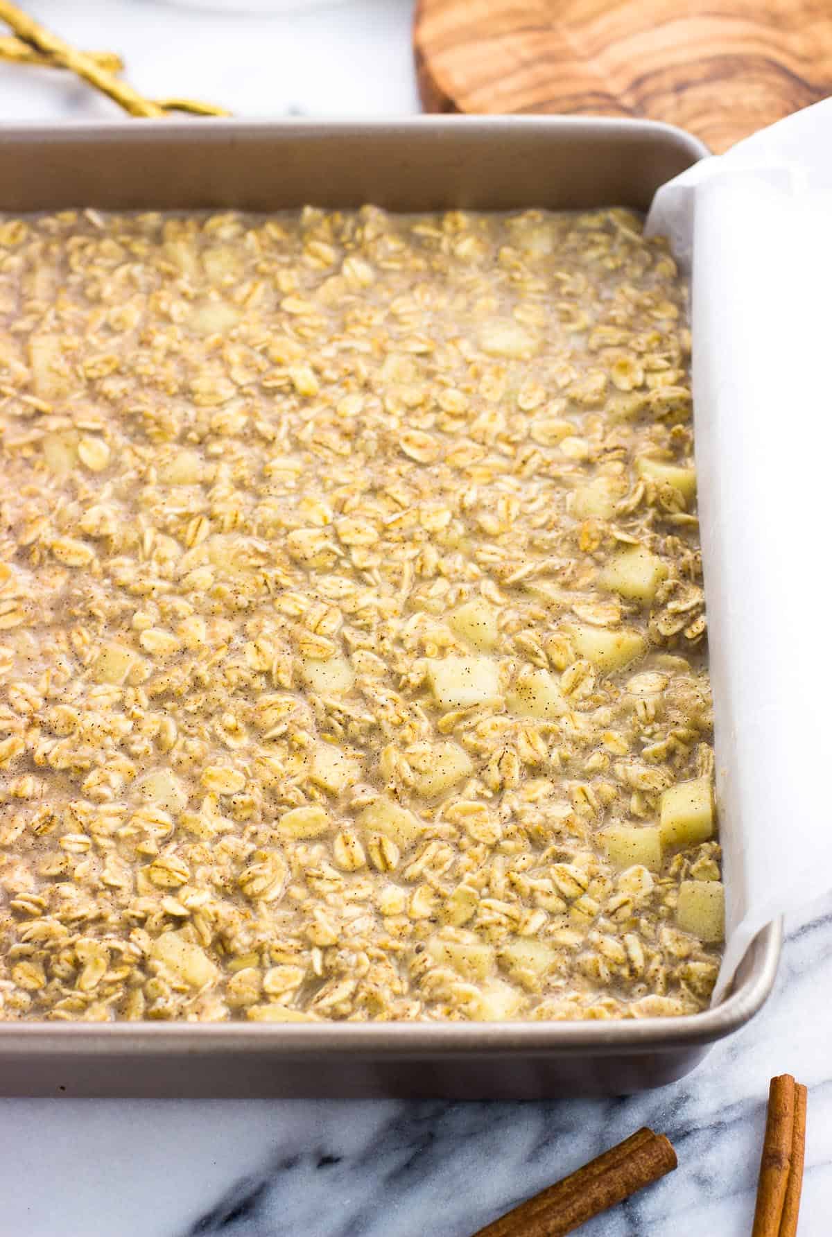 Baked oatmeal mixture poured into a parchment paper-lined square baking dish.