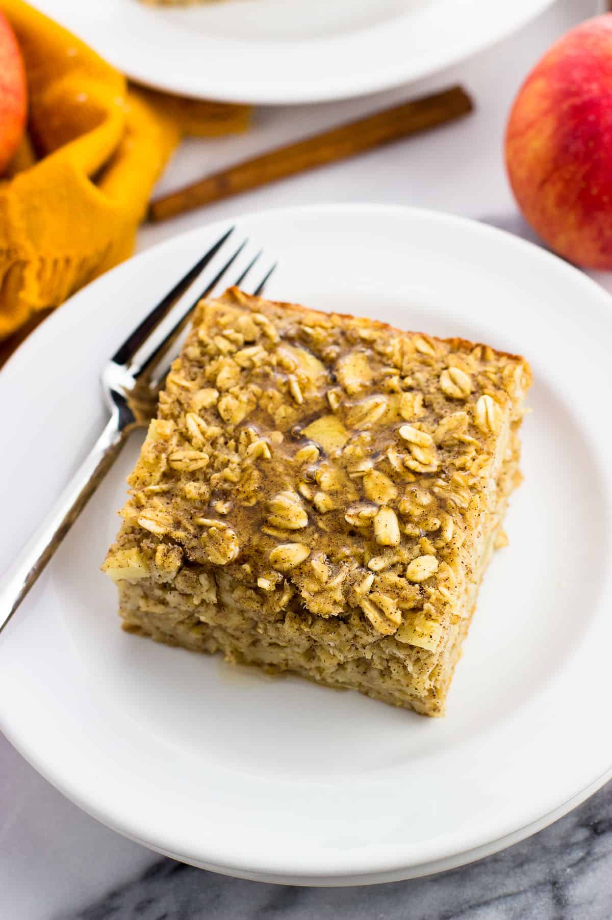 A piece of baked oatmeal on a plate drizzled with maple syrup with a fork.