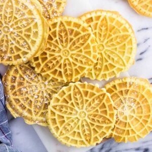 Pizzelle dusted with powdered sugar on a marble board