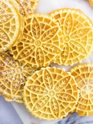 Pizzelle dusted with powdered sugar on a marble board