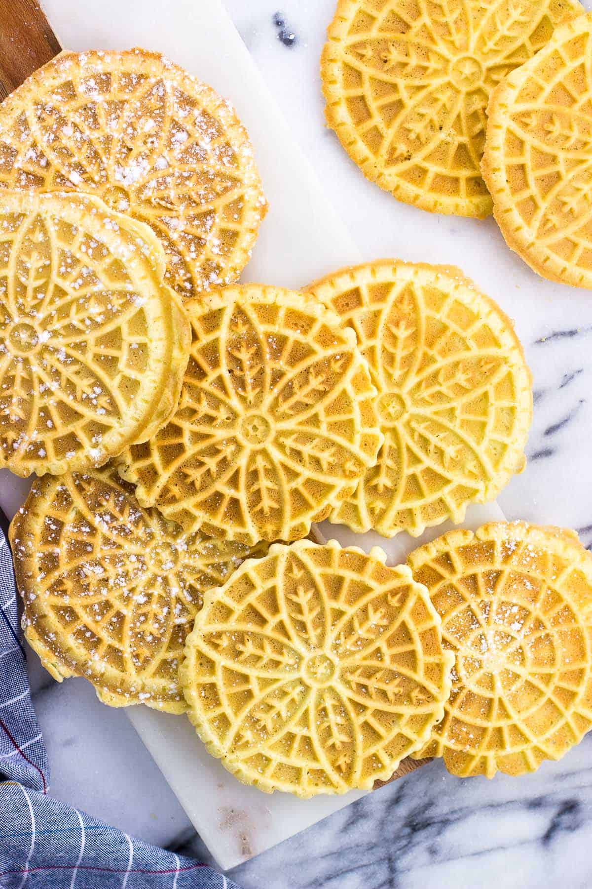 Pizzelle dusted with powdered sugar on a marble board