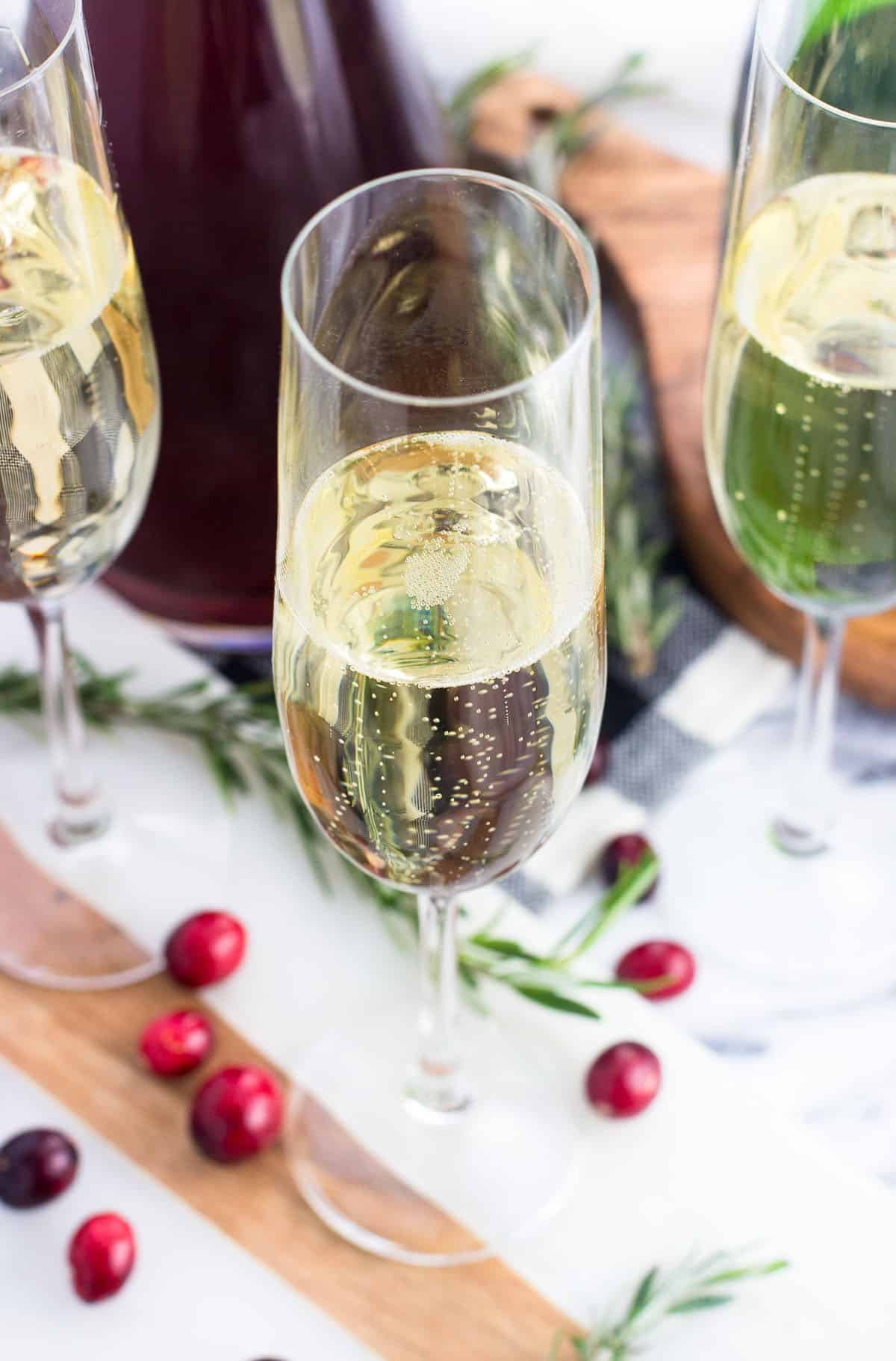 Three champagne flutes all a portion-filled with champagne.