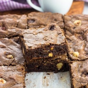 A pan of chocolate hazelnut brownies cut into squares with two brownies stacked on top of one another