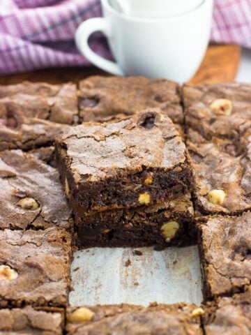 A pan of chocolate hazelnut brownies cut into squares with two brownies stacked on top of one another