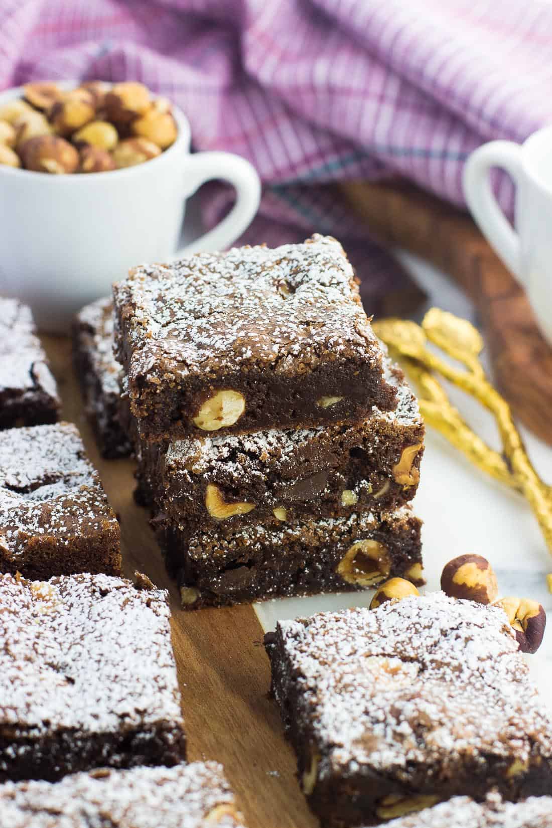 A stack of three hazelnut brownies dusted with powdered sugar