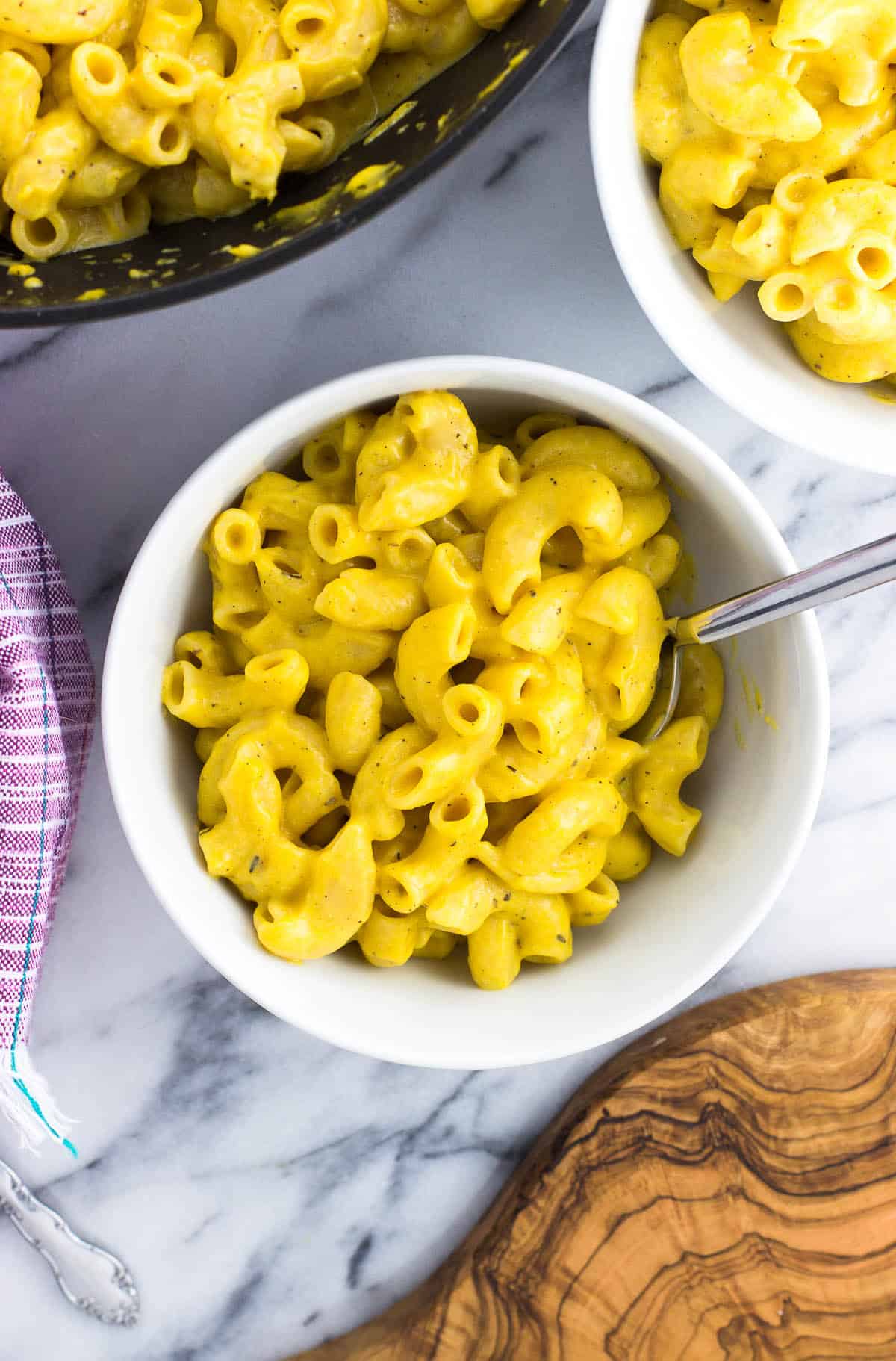 Two bowls of pumpkin mac and cheese next to the pan