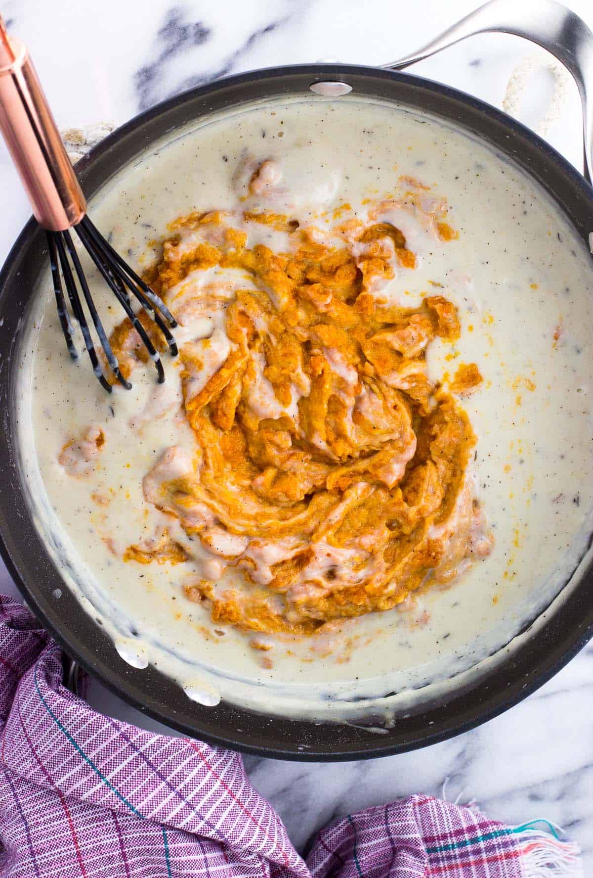 Pumpkin puree being whisked into the roux