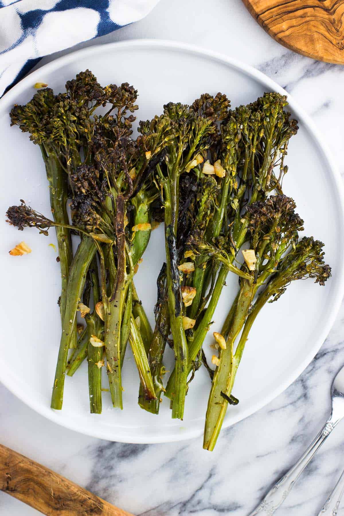 Broccolini on a plate roasted with bits of garlic.