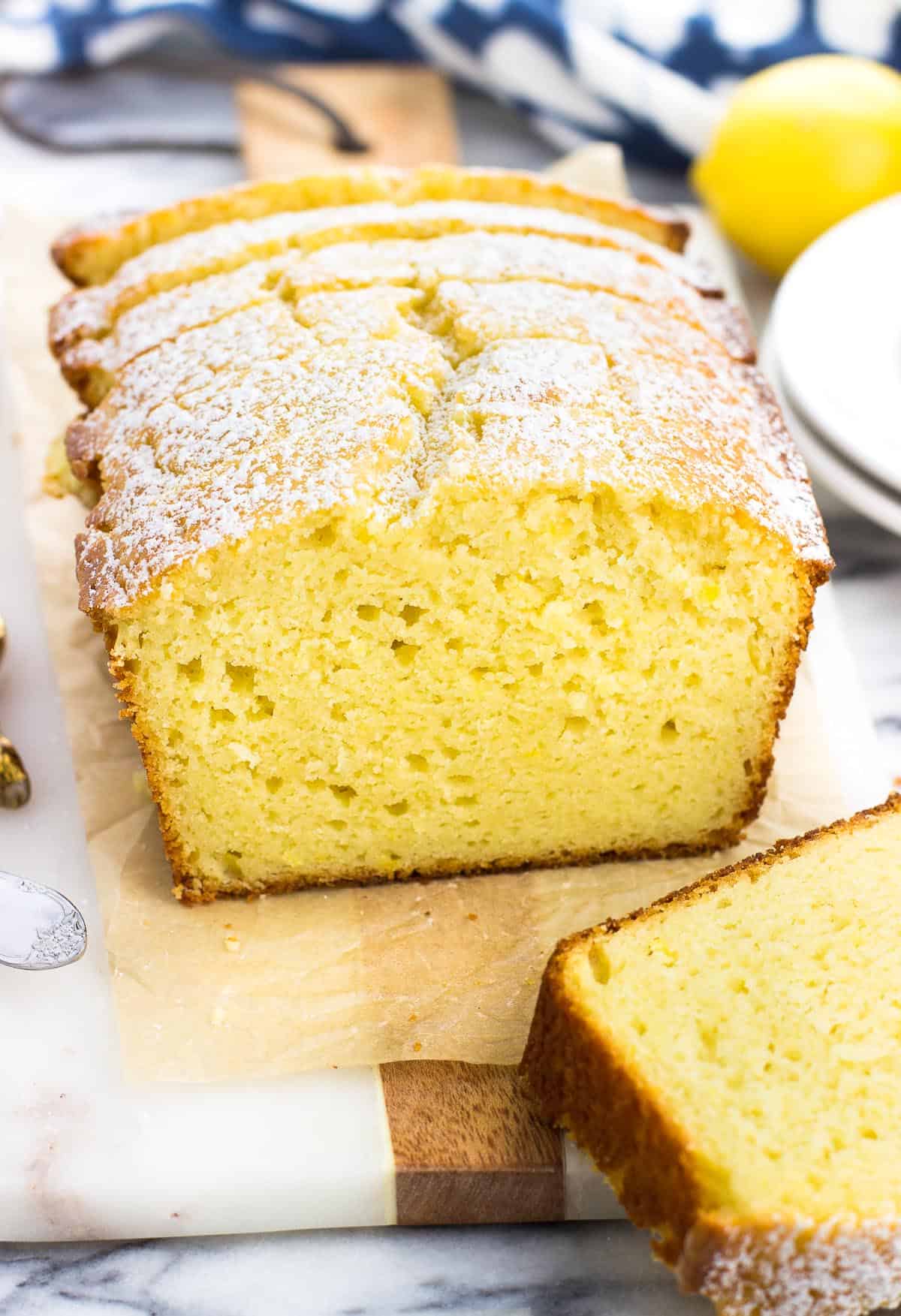 A sliced loaf of lemon yogurt cake on a marble tray.