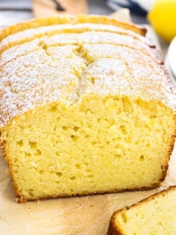 A sliced loaf of lemon yogurt cake on a marble tray.