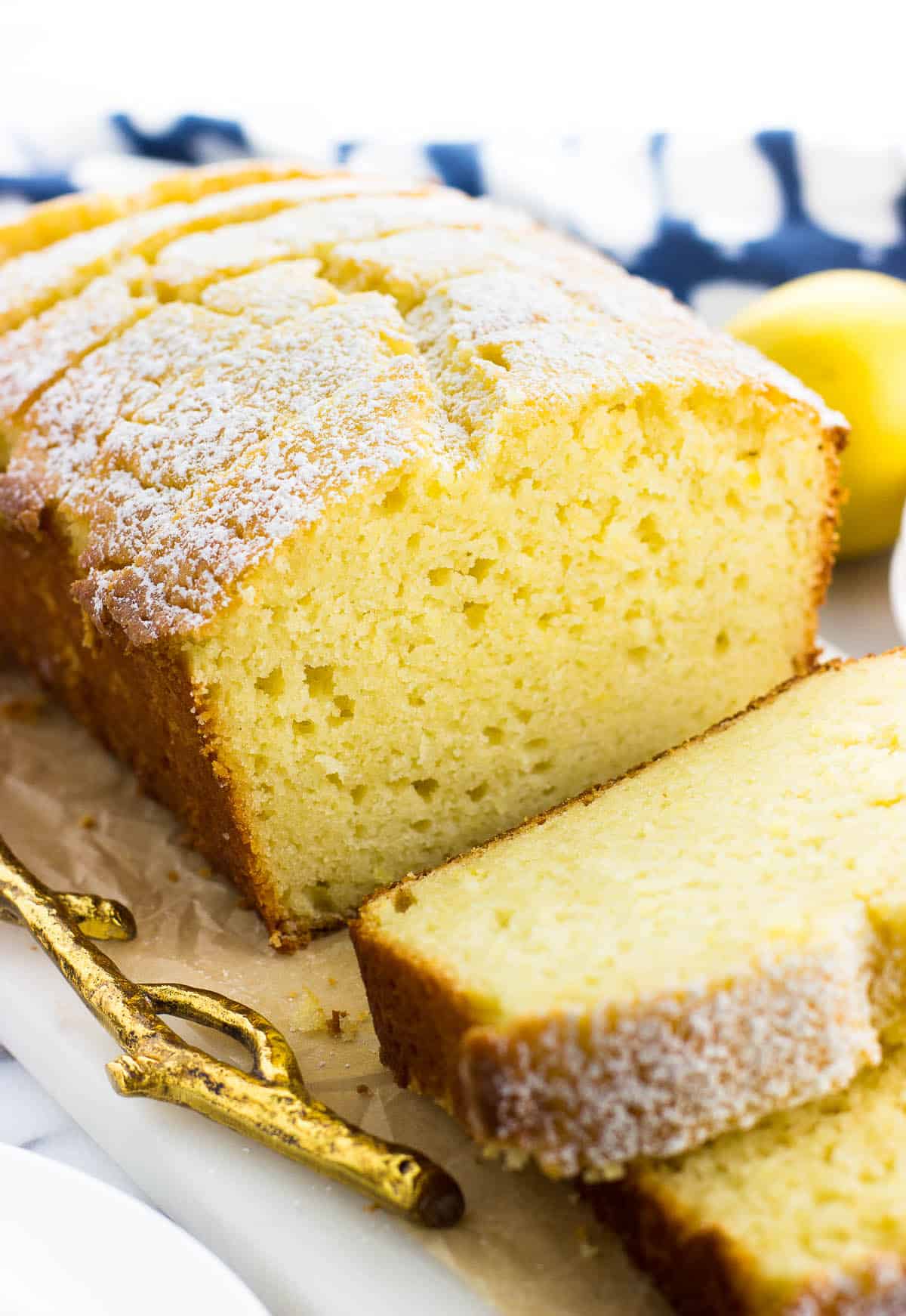 Lemon yogurt cake sliced on a tray dusted with confectioners' sugar.