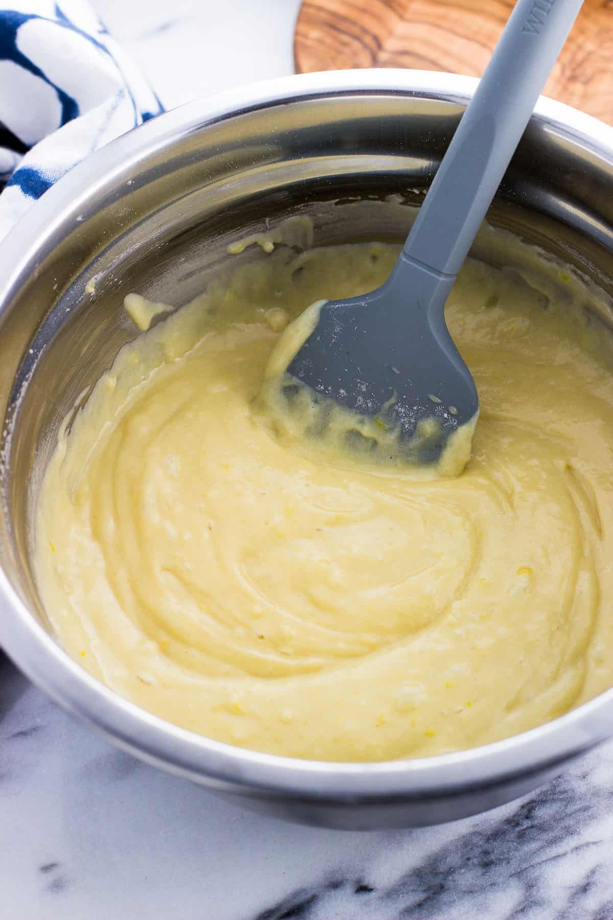Cake batter in a metal mixing bowl with a spatula in it.