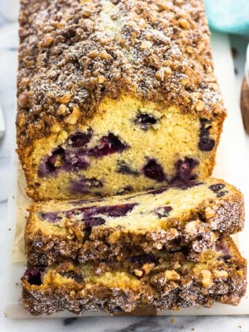 A partially sliced loaf of blueberry bread on a tray.