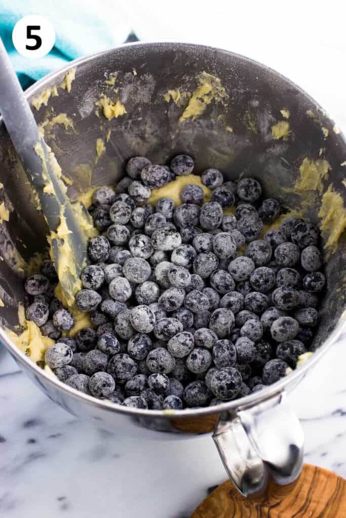 Flour-dusted blueberries poured on top of the batter in the bowl.