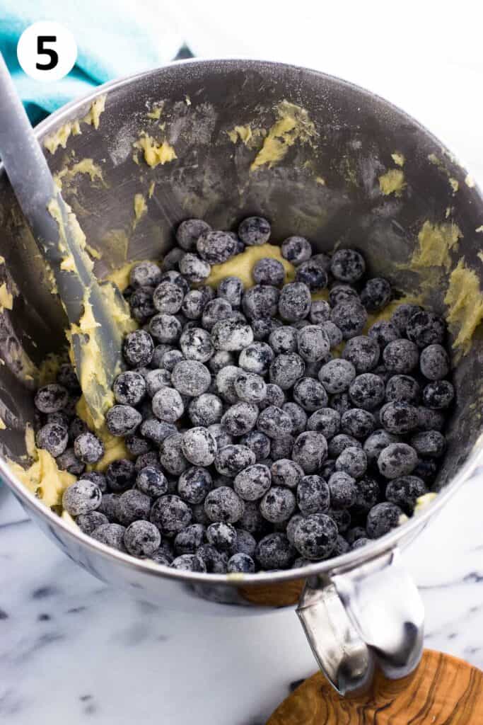 Flour-dusted blueberries poured on top of the batter in the bowl.