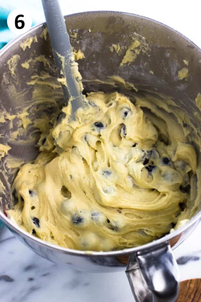 Blueberries folded into the batter with a spatula.