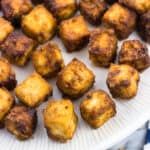 Bite-sized baked tofu cubes on a plate.