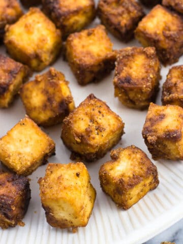 Bite-sized baked tofu cubes on a plate.