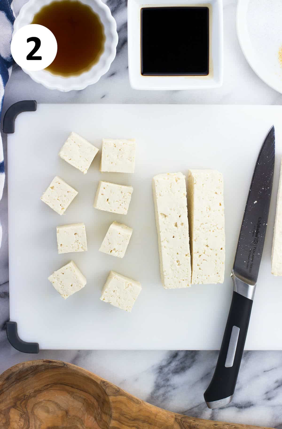 The tofu block being cut into cubes.