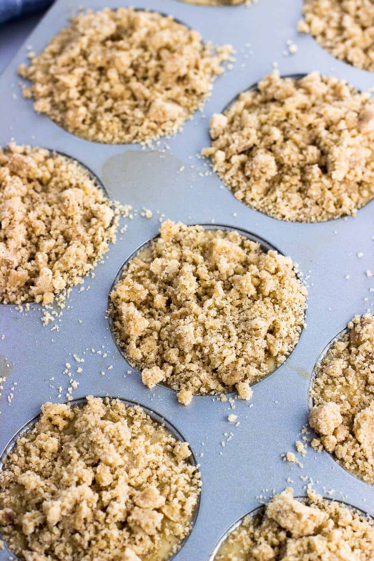 Batter poured into a muffin tin with crumb topping.