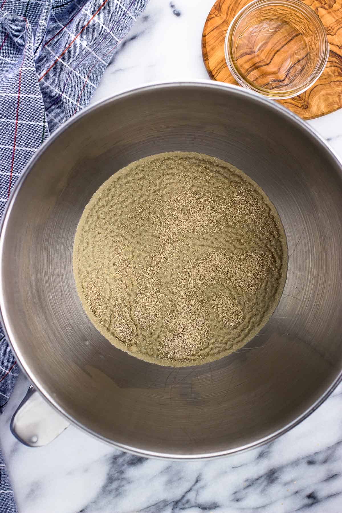 Warm water and sprinkled yeast in a metal stand mixer bowl.