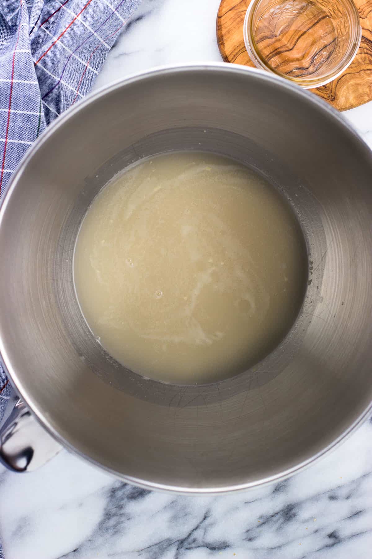 Frothy activated yeast in warm water in a metal stand mixer bowl.