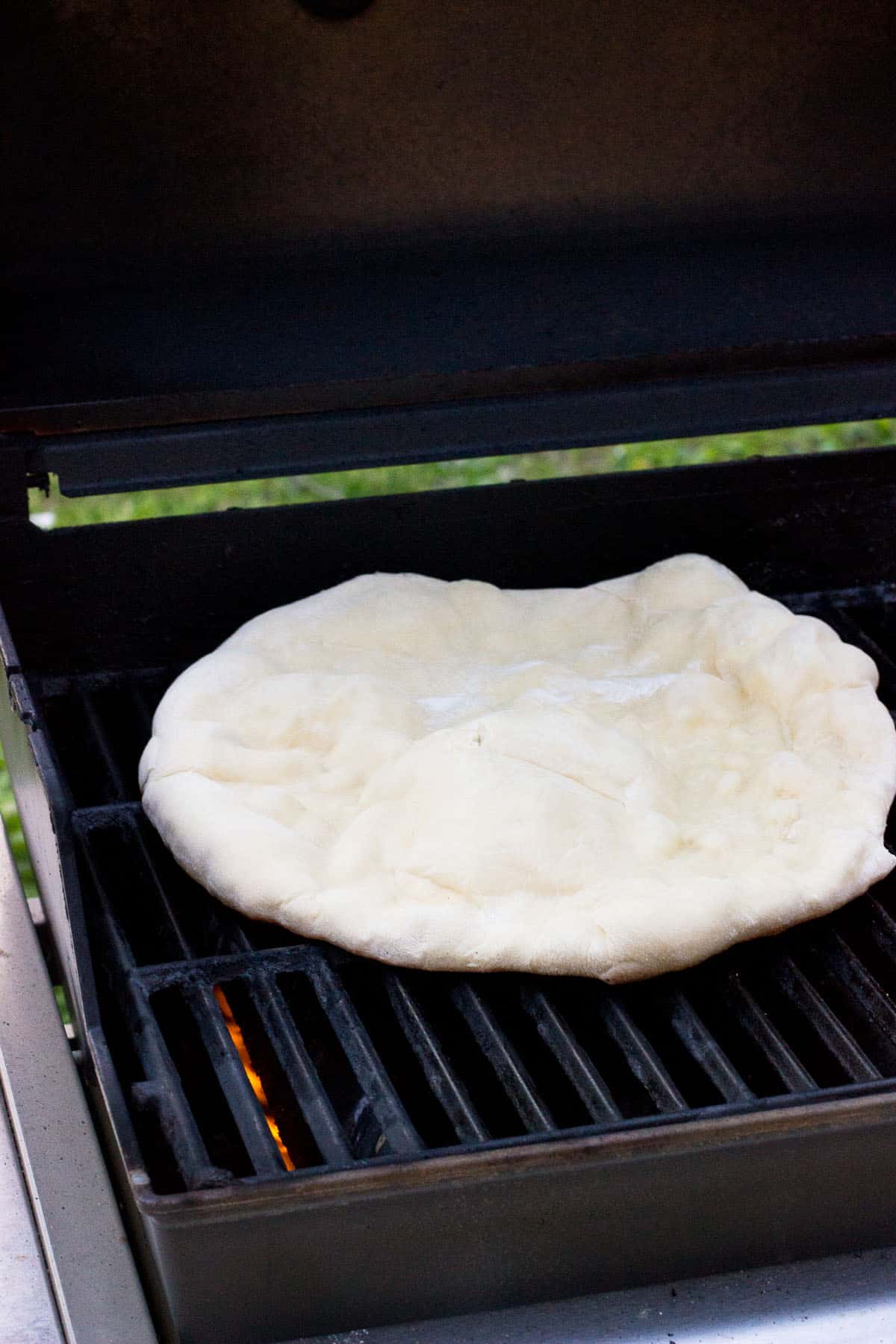 Puffed up pizza dough cooking on a grill.