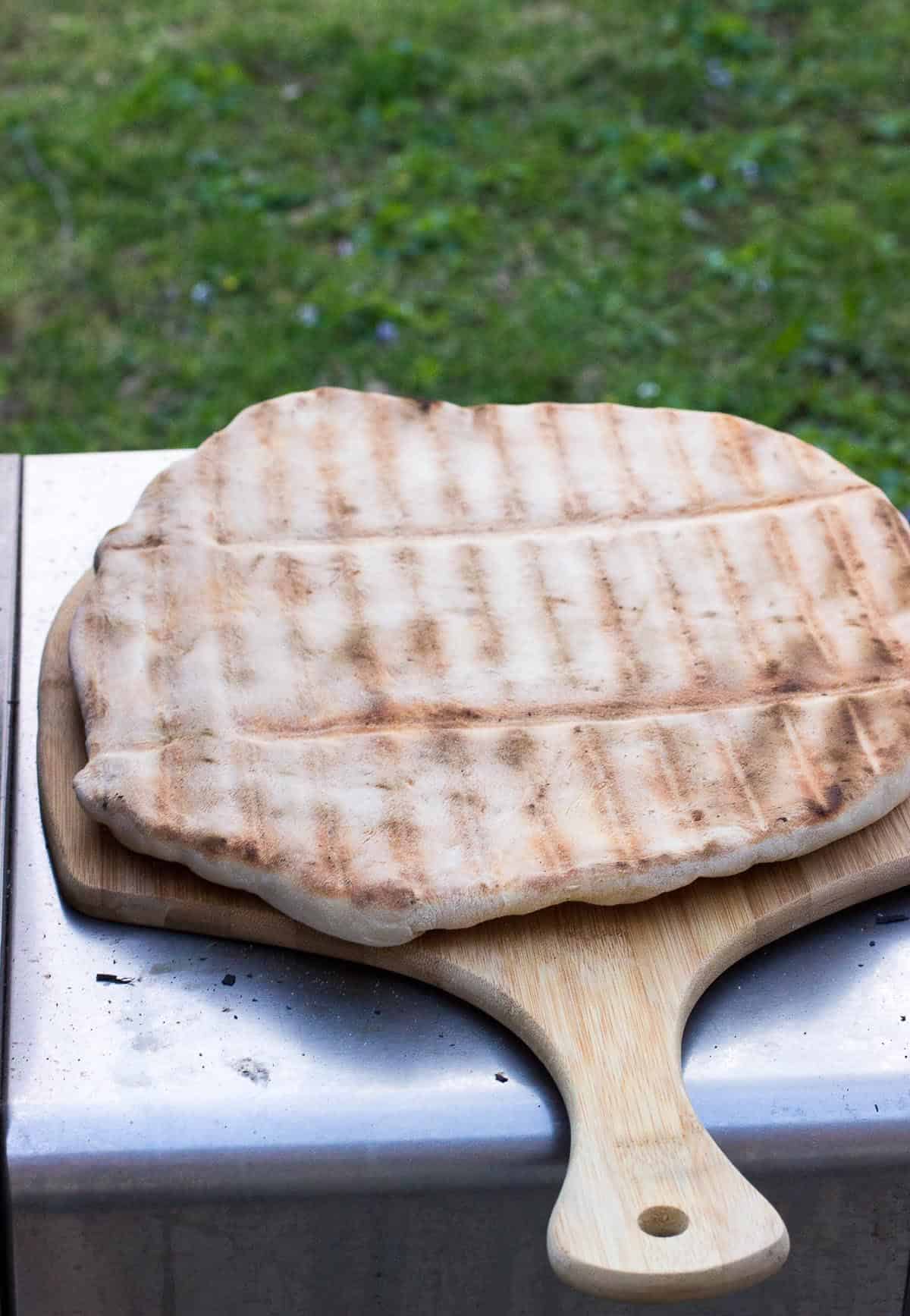 Pizza crust, cooked side up, on a pizza peel.