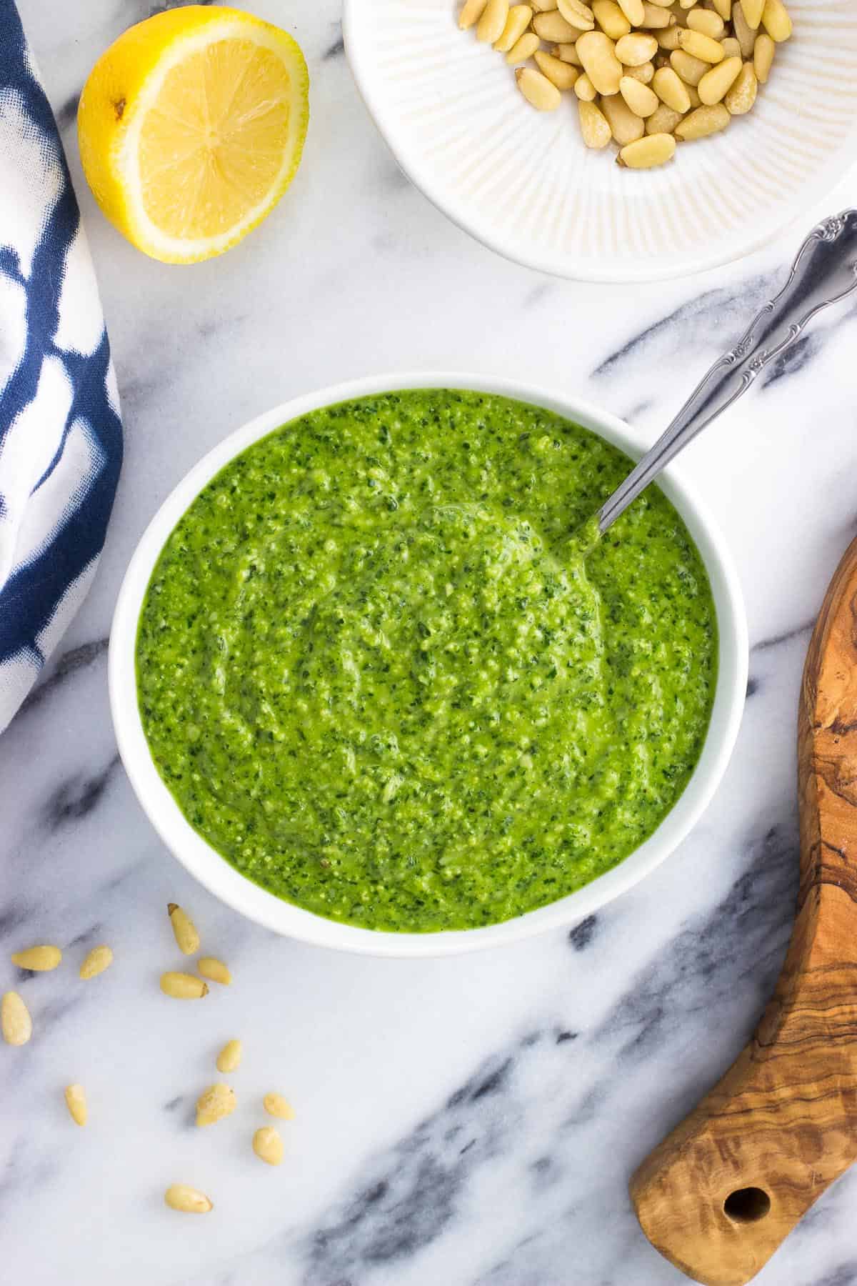 A bowl of spinach pesto with a spoon in it.