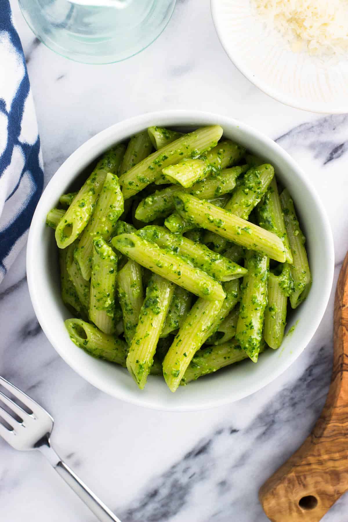 Spinach pesto sauce on penne pasta in a bowl.