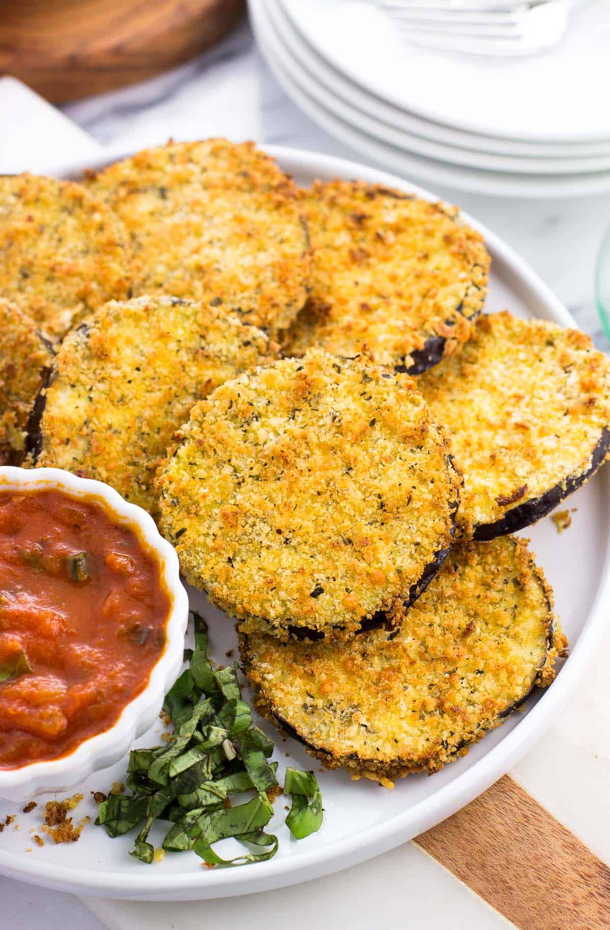 Air fried eggplant rounds on a plate with a bowl of marinara dipping sauce.