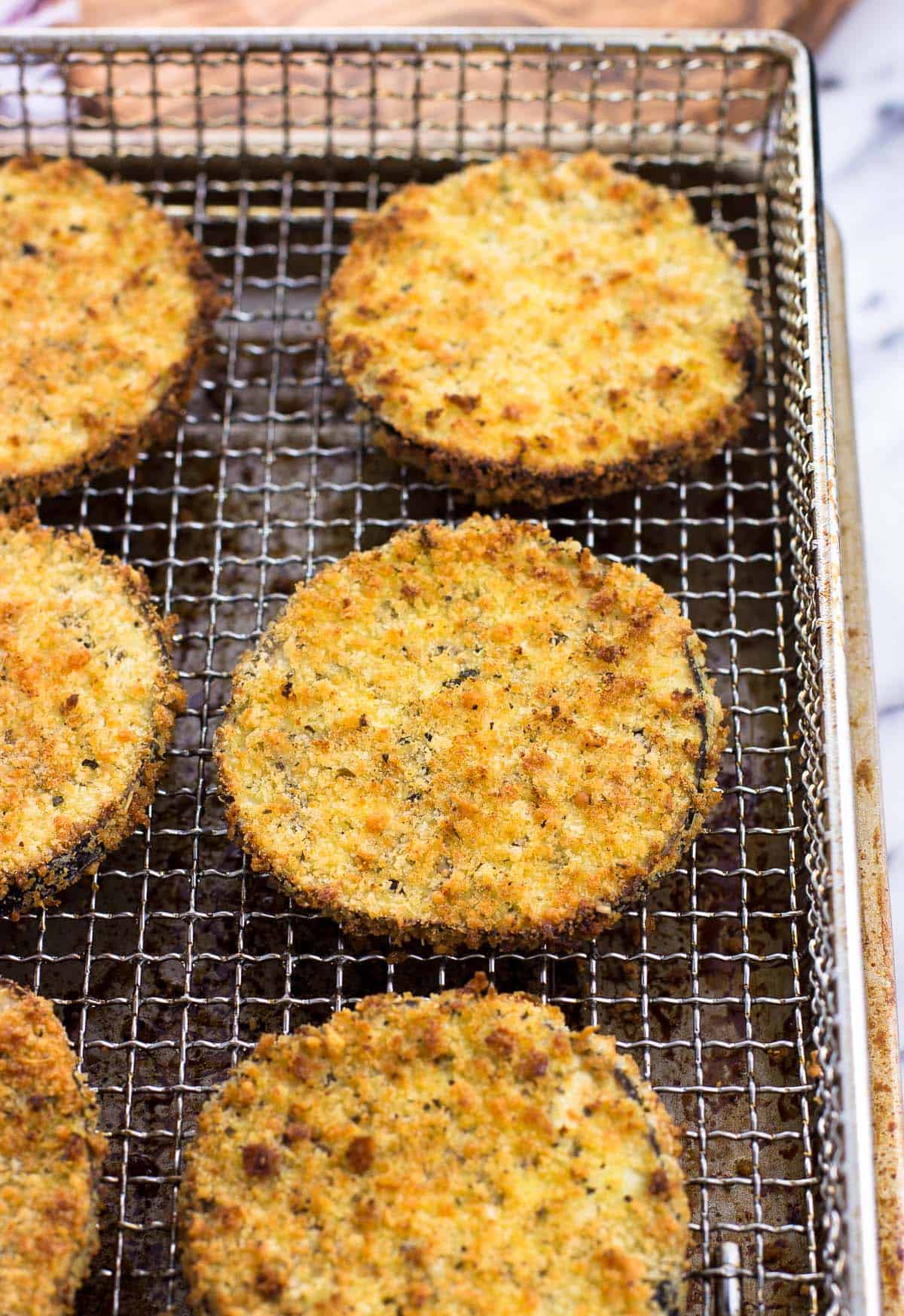 Cooked eggplant slices in an air fryer basket.