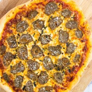 A cooked meatball pizza on a wooden peel.