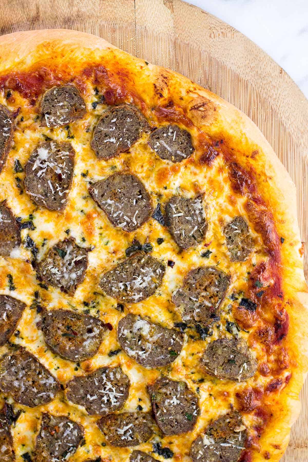 A cooked meatball pizza on a wooden peel.