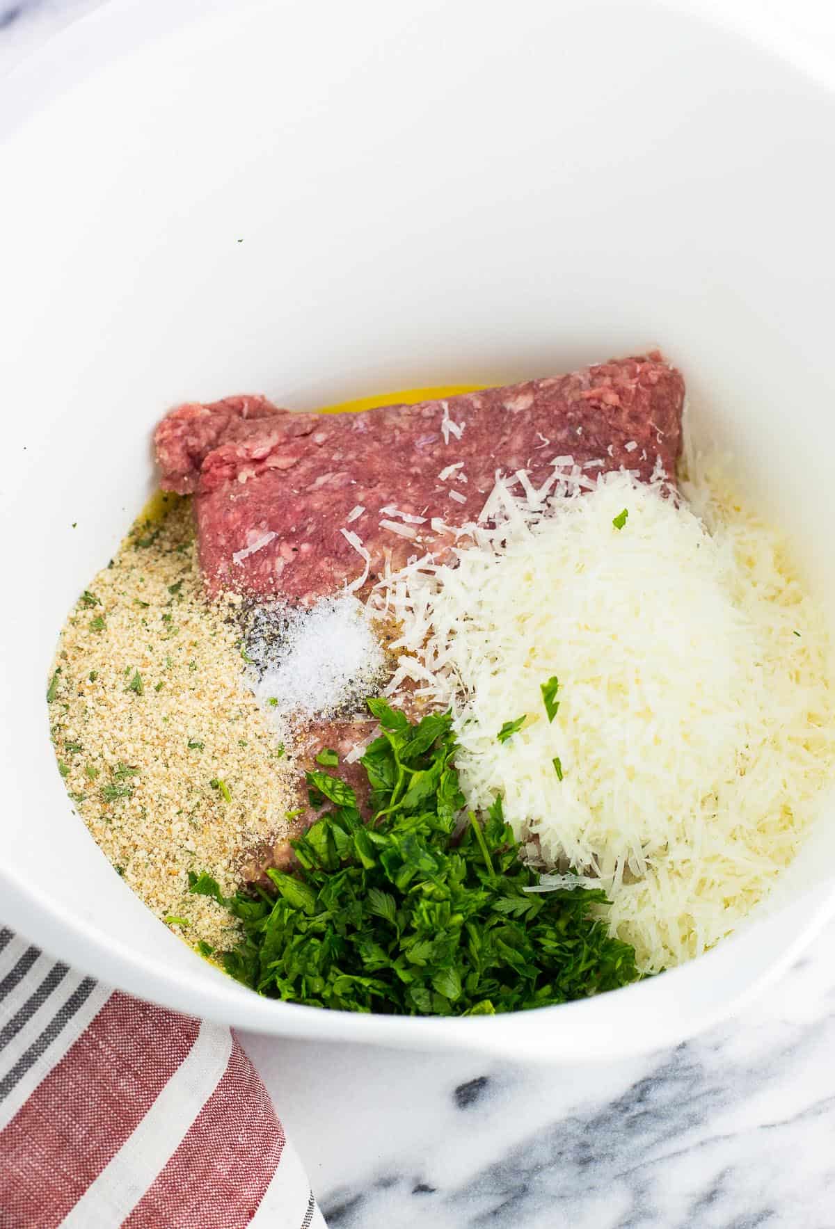 Meatball ingredients added to a large mixing bowl.