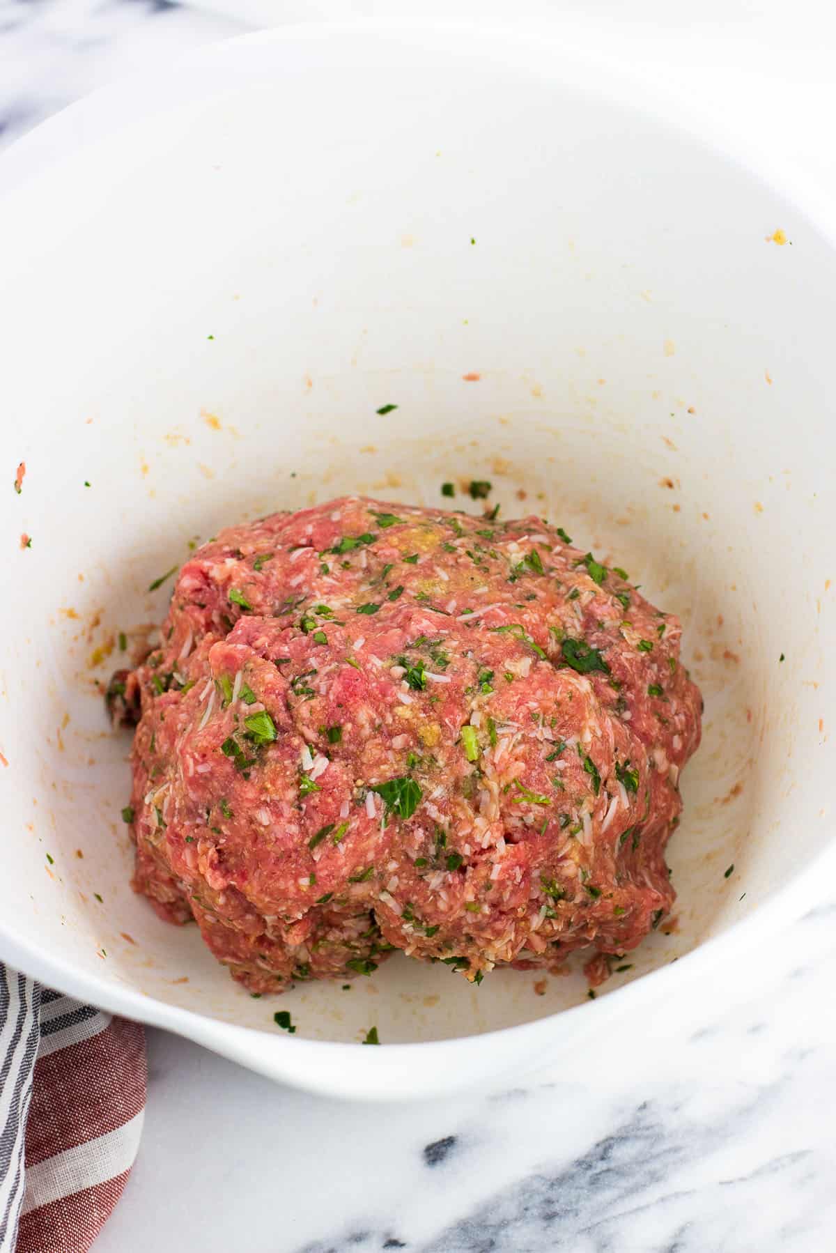 Meatball mixture combined together in a mixing bowl.