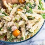A close-up of a bowl of tuna pasta salad with a wooden serving spoon.