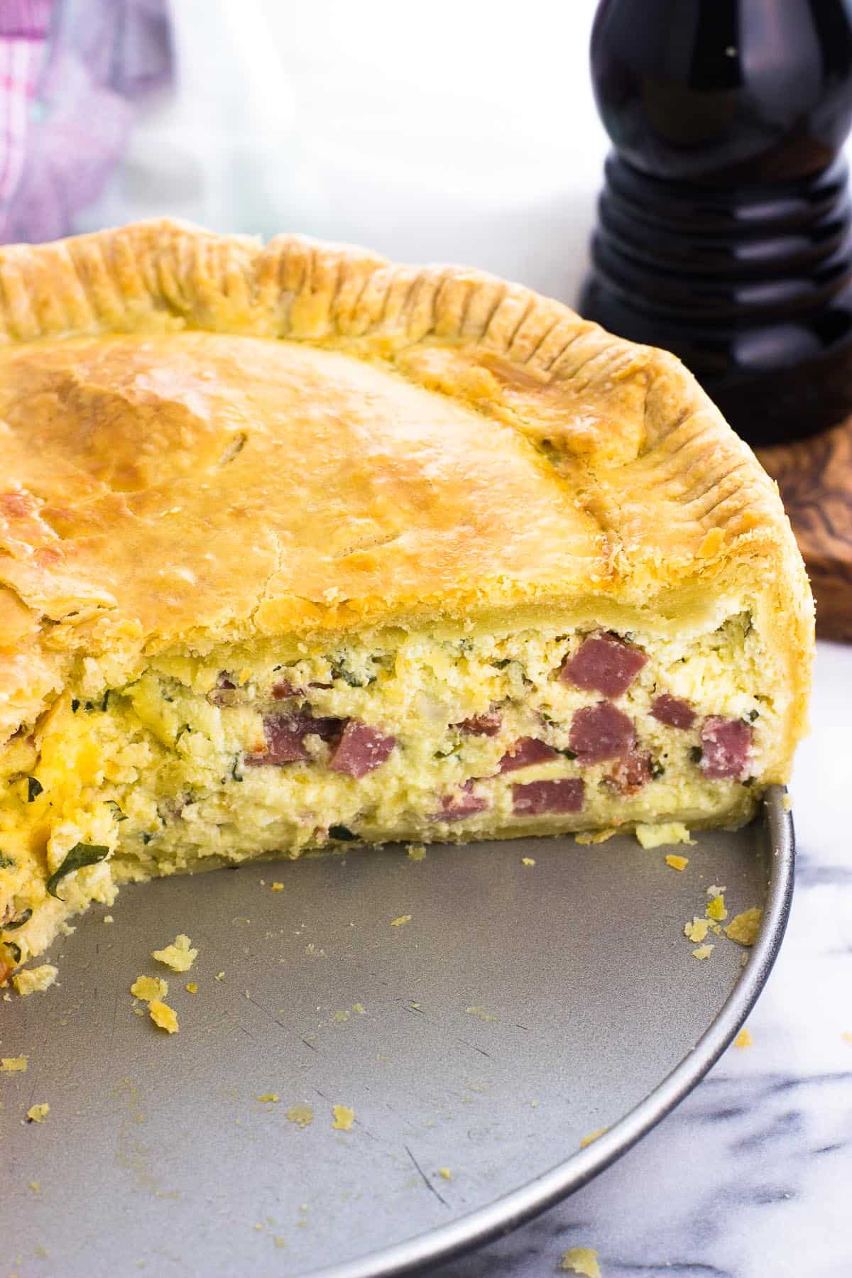 A side view of a sliced open pizza rustica on a pan.