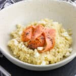 A shallow bowl of risotto topped with smoked salmon slices.