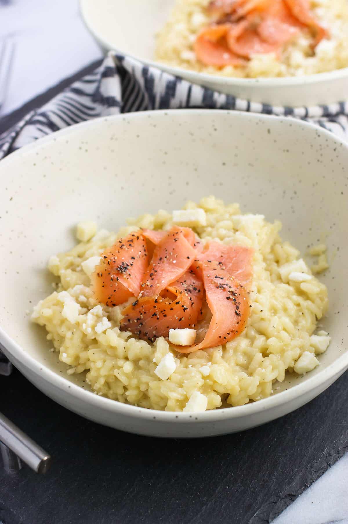 A shallow bowl of risotto topped with smoked salmon slices.