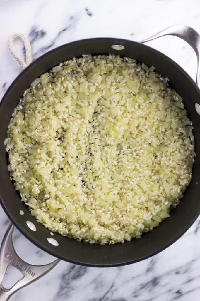 Dry arborio rice added to the pan with onions and garlic.