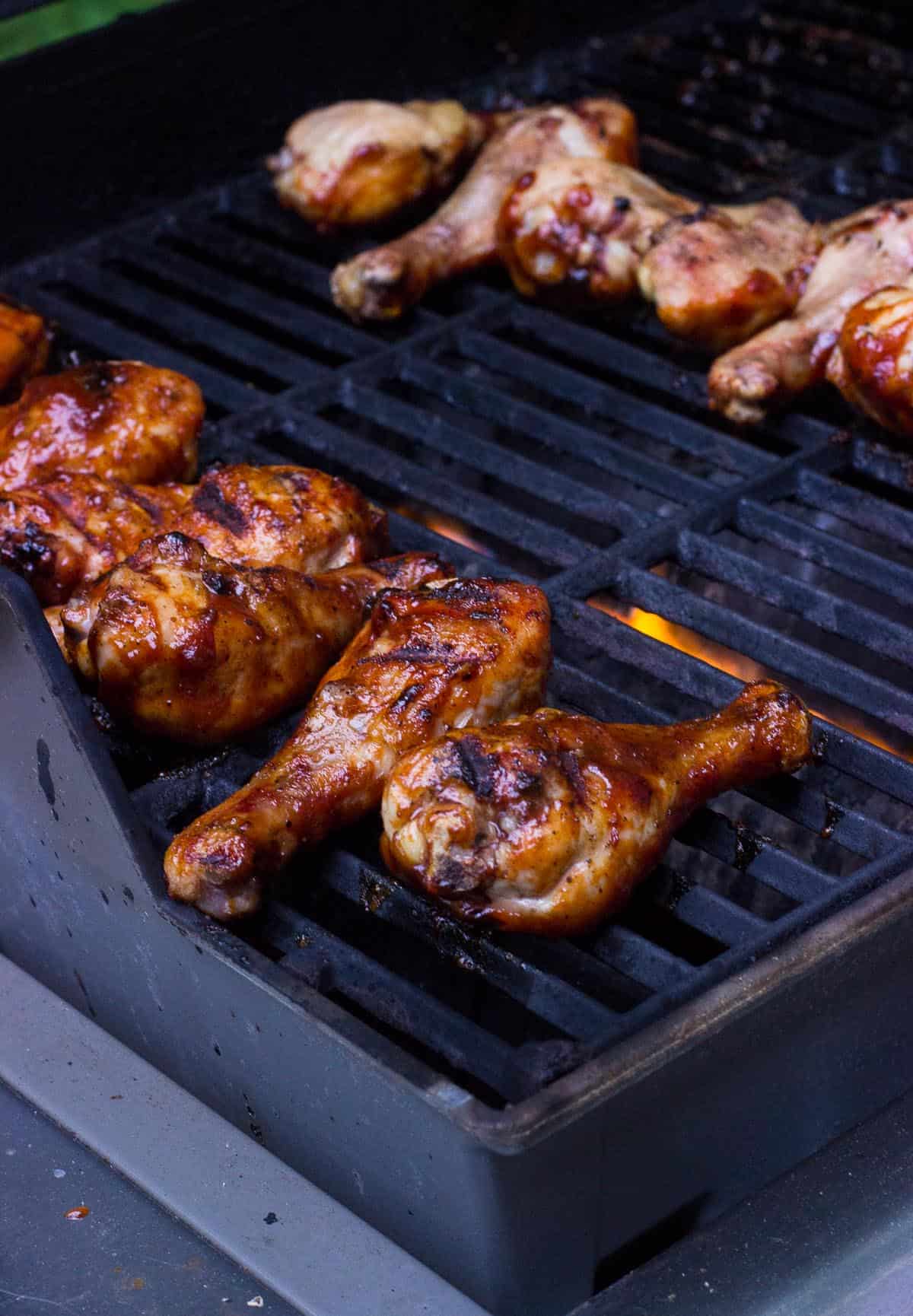 The drumsticks on the grill halfway basted with BBQ sauce.