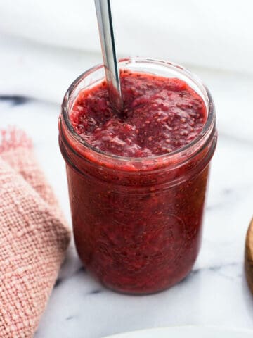 A jar of strawberry chia jam with a spoon in it.